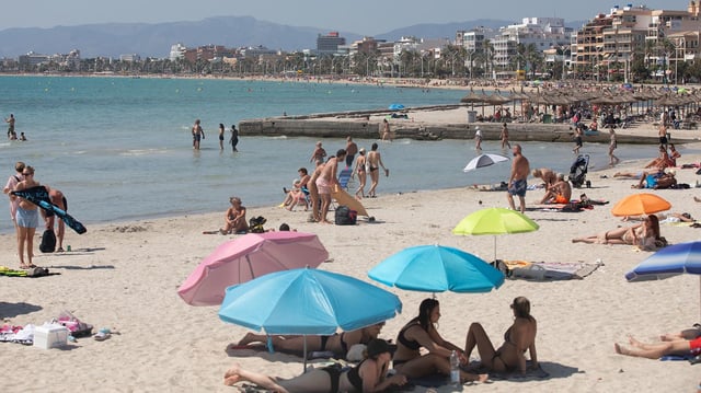 Menschen schwimmen und sonnen sich am Strand von Arenal auf Mallorca.