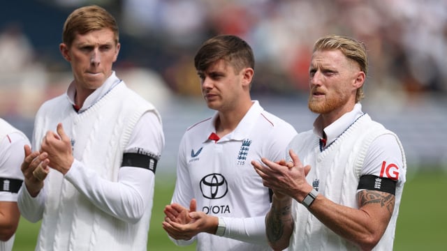 England's Ben Stokes applauds with teammates as they line up during the national anthems before the match