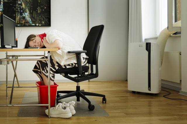 Eine Frau sitzt bei starker Hitze in einem Büro (Symbolbild).