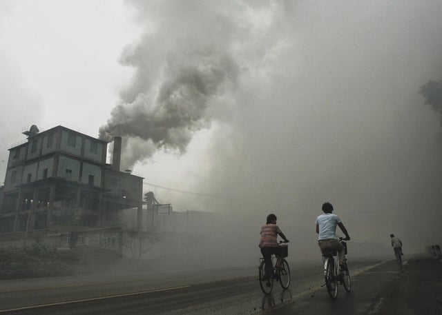 Unos ciudadanos pasan al lado de una central de carbón en China.