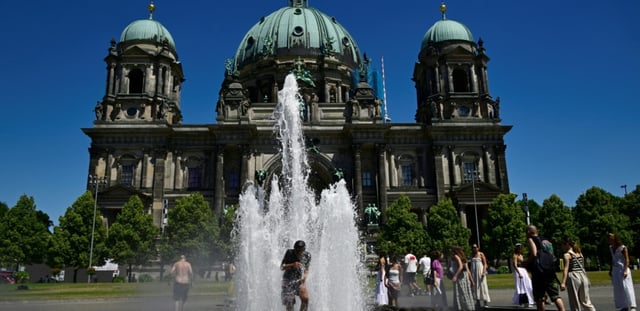 Des personnes se rafraîchissent dans l'eau d'une fontaine, le 2 juillet 2025 à Berlin