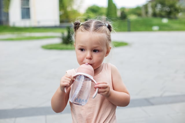 Two year old drinking from plastic sippy cup.