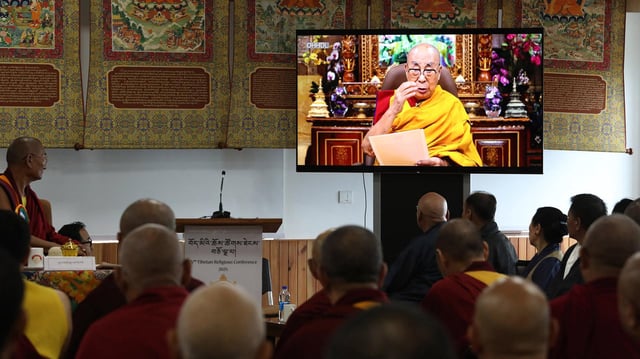 Der Dalai Lama ist auf einem Fernsehbildschirm zu sehen.