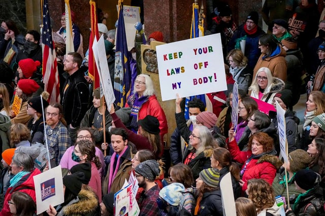 People hold signs at the Capitol rotunda in Madison, Wis., on Jan. 22, 2023.