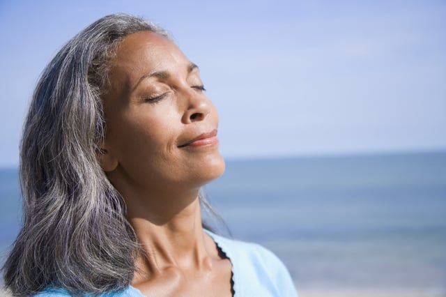 Close-up of a mature woman smiling with her eyes closed.