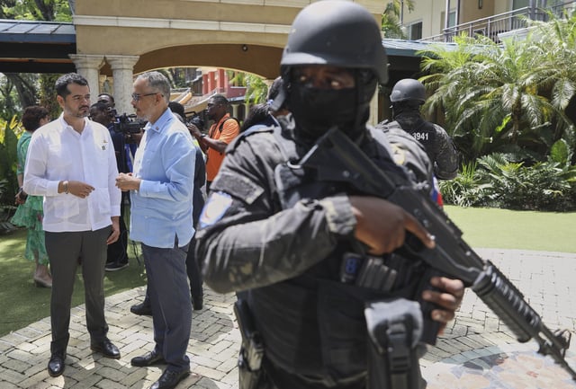 Security guards stand watch as Haiti's Prime Minister Alix Didier Fils-Aime, center, talks with the Mexico's Charge d'Affaires Jesus Cisneros after attending an event marking one year since the start of the Multinational Security Support Mission in Port-au-Prince, Haiti, Thursday, June 26, 2025. (AP Photo/Odelyn Joseph)