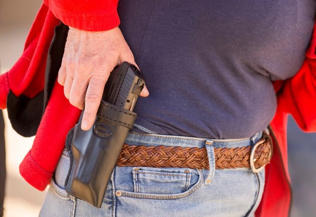 A student training for a license to carry a concealed weapon pulls back her coat to draw and shoot during an Allsafe Defense Systems class in Chino in 2016. (File photo by Jebb Harris, Zuma Wire.)