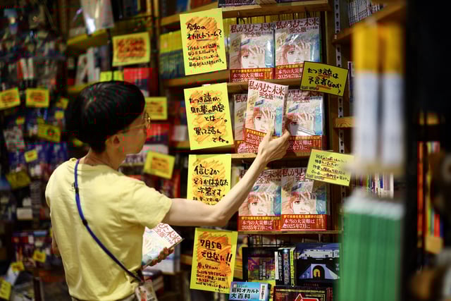 A member of staff places the comic book titled 'The Future I saw', authored by manga artist Ryo Tatsuki, on the shelf at Village Vanguard book store in Tokyo, Japan June 30, 2025. REUTERS/Issei Kato/File Photo