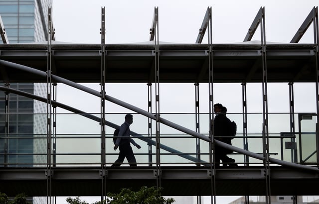 Businessmen wearing protective face masks walk on a pedestrian bridge in a business district in Tokyo, Japan June 24, 2020. REUTERS/Issei Kato/ File Photo
