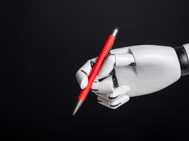 A robotic hand holding a red pen on a black background, blending modern technology with timeless utility
