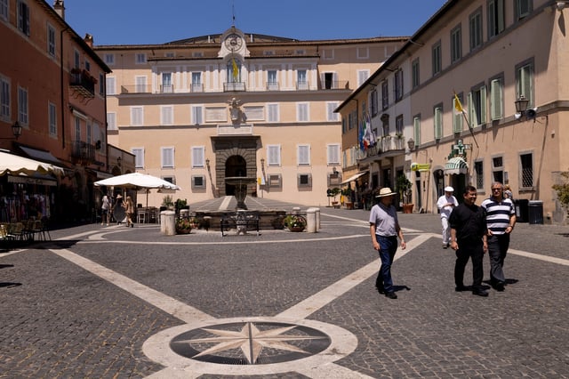 People walk in front of the Apostolic Palace in the central square of the town of Castel Gandolfo, near Rome, Italy, July 1, 2025. REUTERS/Remo Casilli