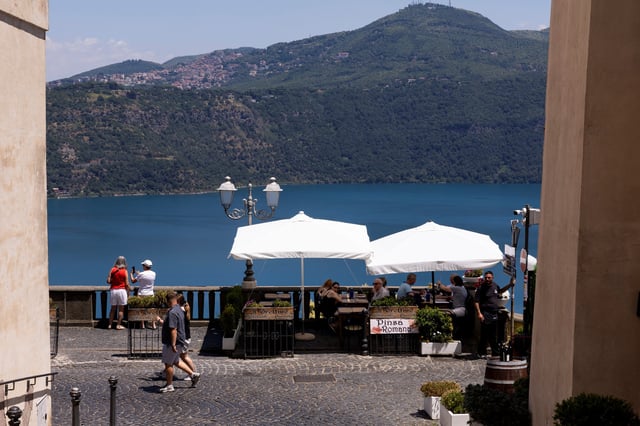 People sit at a restaurant overlooking Lake Albano in Castel Gandolfo, near Rome, where Pope Leo will spend two weeks of vacation in July, Italy, July 1, 2025. REUTERS/Remo Casilli