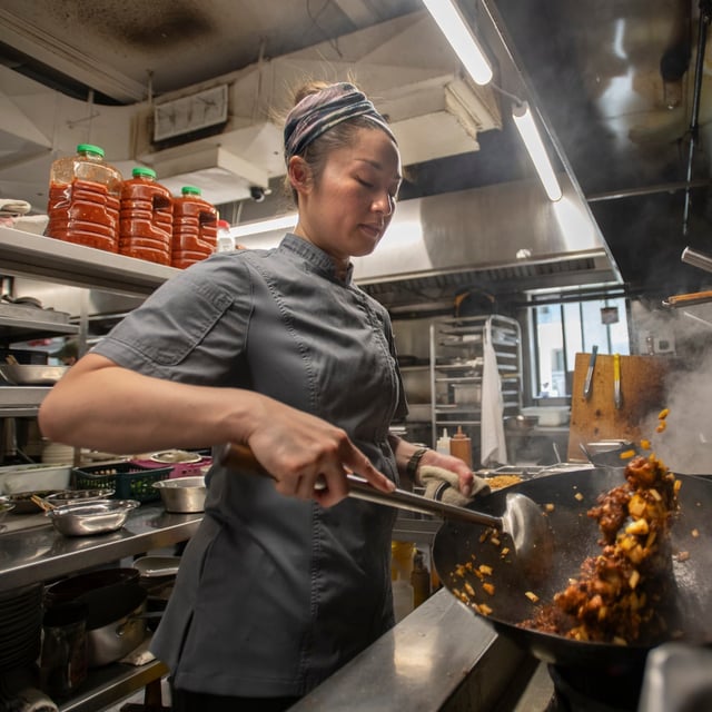 Joanna Liu, one of few female chefs running a Chinese kitchen, prepares a child chicken dry dish in one of the woks over a roaring flame at Yueh Tung on June 17,2025. Joanna Liu and her sister Jeanette Liu took over the Hakka resturant from their parents. (Fred Lum/The Globe and Mail)