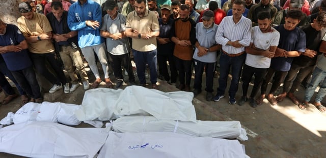 Des Palestiniens se recueillent devant des corps enveloppés dans des draps blancs, le 3 juillet 2025 dans la ville de Gaza