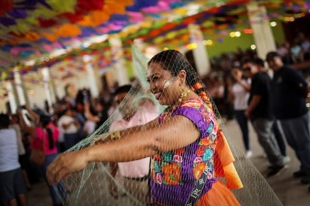 A woman caught in a fishing net during a symbolic marriage ritual of a female caiman named "princess girl" Miguelana Estela del Mar Zavaleta Ramirez, a reptile that closely resembles an alligator, and San Pedro Huamelula mayor Daniel Gutierrez Pena, which is rooted in more than 230 years of tradition and joins two of Oaxaca state's indigenous cultures, the Chontal and the Huave, to plead for nature's bounty, in San Pedro Huamelula, Mexico, June 30, 2025. REUTERS/Raquel Cunha