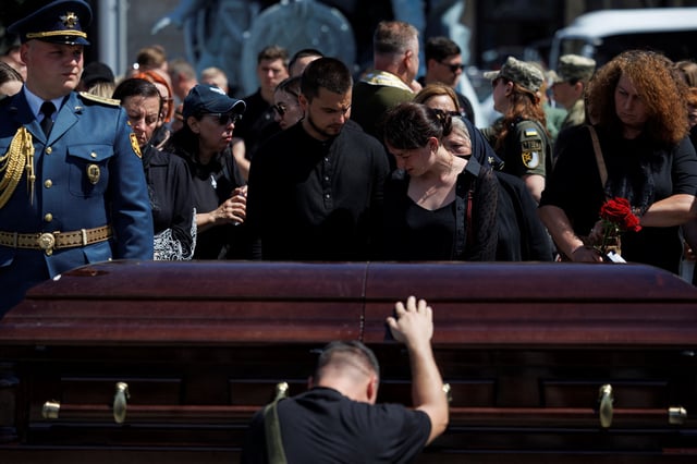 Relatives react next to a coffin with the body of Ukrainian military pilot Colonel Maksym Ustymenko, who died last Sunday operating an F16 fighter jet during a combat mission, amid Russia's attack on Ukraine, during his funeral ceremony at the Independence Square in Kyiv, Ukraine July 3, 2025.  REUTERS/Valentyn Ogirenko