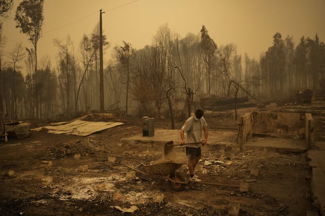 FILE - Yeremy Escanilla works on cleaning the debris of the remains of his house, destroyed by wildfires in Santa Juana, Chile, Feb. 5, 2023. (AP Photo/Matias Delacroix, File)