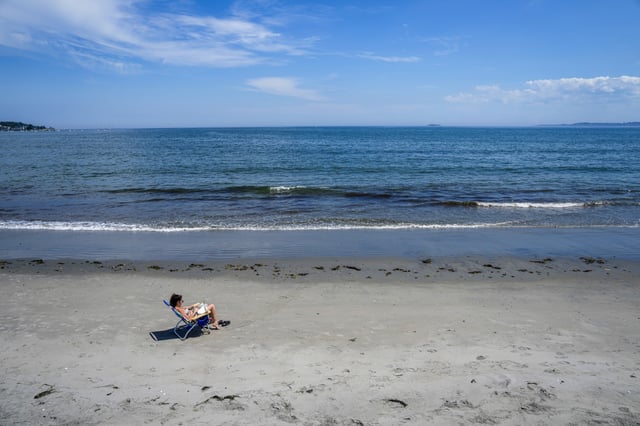 A woman relaxes on the sand at the beach in Lynn, Mass., on July 8, 2024.