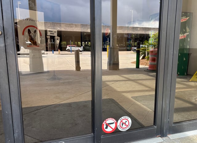 Entrance signage at Oglethorpe Mall informs visitors of the presence of a drug-detection dog and prohibits the carrying of firearms.
