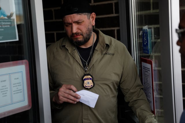 An ICE agent talks with migrants about their scheduled appointments with U.S. Immigration and Customs Enforcement (ICE) on Father’s Day, to learn about their immigration status, in Chicago, Illinois., U.S., June 15, 2025. REUTERS/Octavio Jones/File Photo