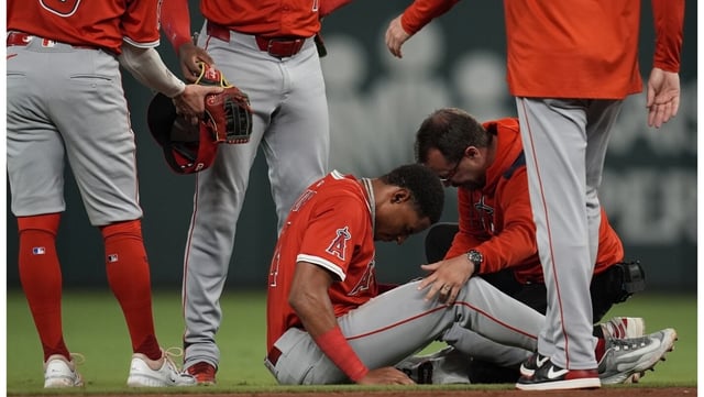 Angels second baseman Christian Moore is helped by a trainer after injuring his hand while diving to try and field a ground ball hit by the Atlanta Braves’ Ozzie Albies during the sixth inning on Wednesday night in Atlanta. (AP Photo/Mike Stewart)