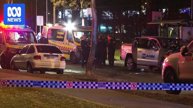 A crime scene at night with police tape, parked cars nearby and ambulance and police vehicles.