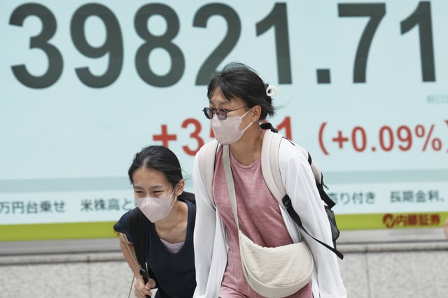 People walk in front of an electronic stock board showing Japan's Nikkei index at a securities firm Friday, July 4, 2025, in Tokyo. (AP Photo/Eugene Hoshiko)