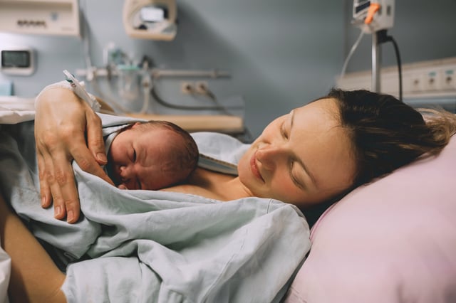 Young mom hugging her newborn baby after delivery.