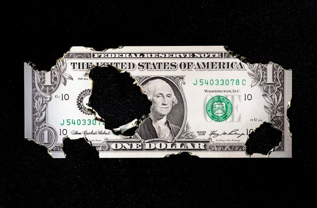 US-Dollar-Schein mit Brandlöchern, Symbolbild Staatsverschuldung der USA