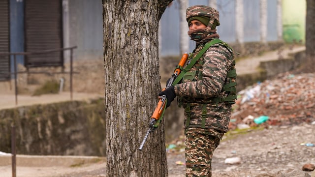 A security personnel stands guard near the site of the encounter, at Gujjarpati area in Sopore, Baramulla district of Jammu and Kashmir,
