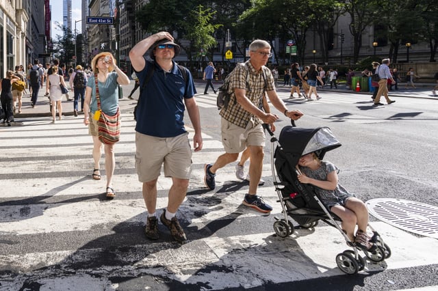 New Yorkers cross 41st Street and Fifth Avenue in Manhattan during a heatwave on June 25, 2025 in New York City.