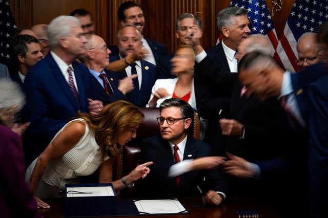 Republican members of Congress reach to shake hands with Speaker of the House Mike Johnson, R-La., center bottom, after Johnson signed President Donald Trump’s signature bill of tax breaks and spending cuts, Thursday, July 3, 2025, at the Capitol in Washington. (AP Photo/Julia Demaree Nikhinson)