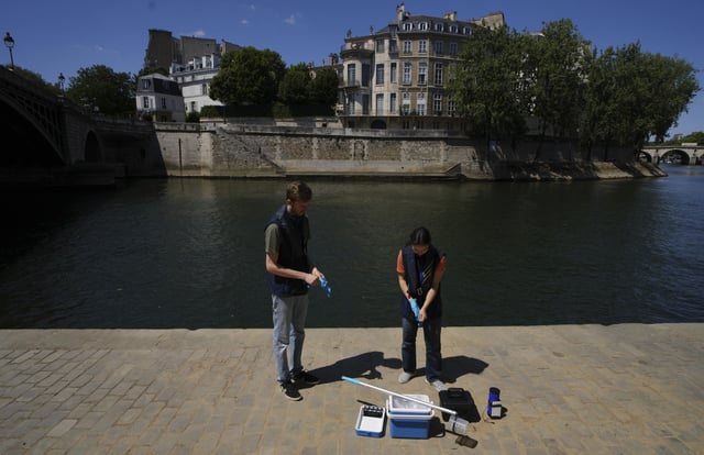 Mathias Hajeut, left, and Emilie Vilana of Fluidion test the Seine river water quality, Thursday, July 3, 2025 for the opening of the three Seine swimming pools during the 'Paris Plages' event from July 5 to Aug. 31 in Paris. (AP Photo/Aurelien Morissard)