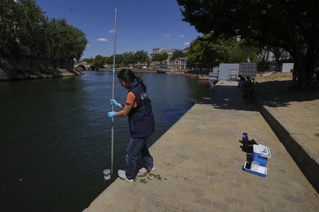 Emilie Vilana of Fluidion takes a sample from the Seine river to test the water quality, Thursday, July 3, 2025 for the opening of the three Seine swimming pools during the 'Paris Plages' event from July 5 to Aug. 31 in Paris. (AP Photo/Aurelien Morissard)