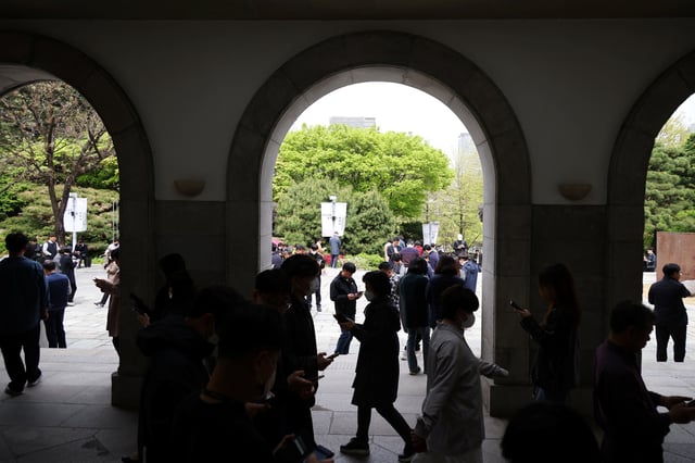 Office workers look at their mobile phones to check the local online banking app Toss as they gather at Seoul Museum of Art during a lunch break in Seoul, South Korea, April 13, 2023.  REUTERS/Kim Hong-Ji/File Photo