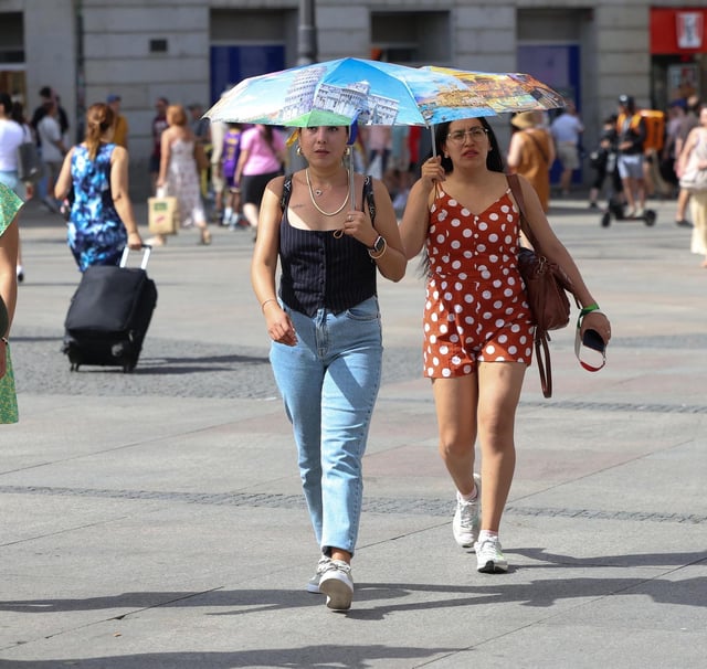 Archivo - Dos personas usan un paraguas para protegerse del sol, a 30 de julio de 2024, en Madrid (España).
