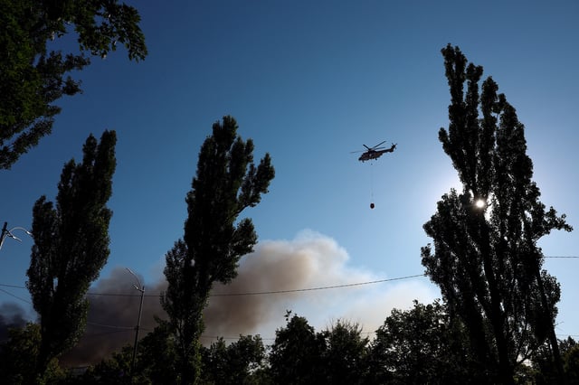 A firefighting helicopter flies over the site of Russian drone and missile strikes, amid Russia's attack on Ukraine, in Kyiv, Ukraine July 4, 2025. REUTERS/Valentyn Ogirenko