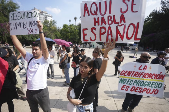 Demonstrators hold posters that read in Spanish ¨Here we speak Spanish, Real Estate Regulation Now¨, during a protest against gentrification, as the increase in remote workers has risen prices and increased housing demand in neighborhoods like Condesa and Roma, in Mexico City, Friday, July 4, 2025. (AP Photo/Fernando Llano)
