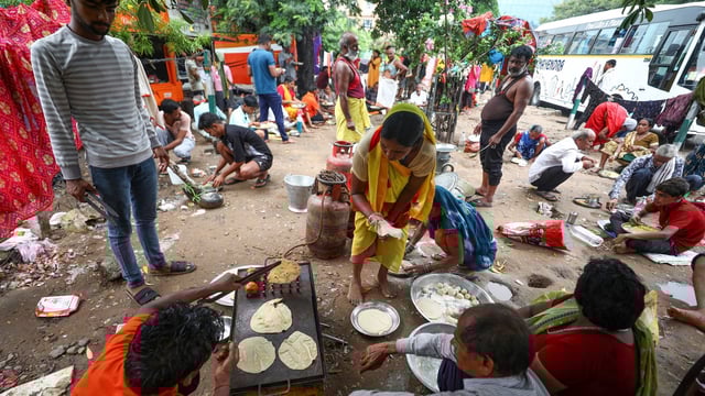 Pilgrims prepare food under a tree as they wait to get themselves registered for the annual Amarnath Yatra, in Jammu.