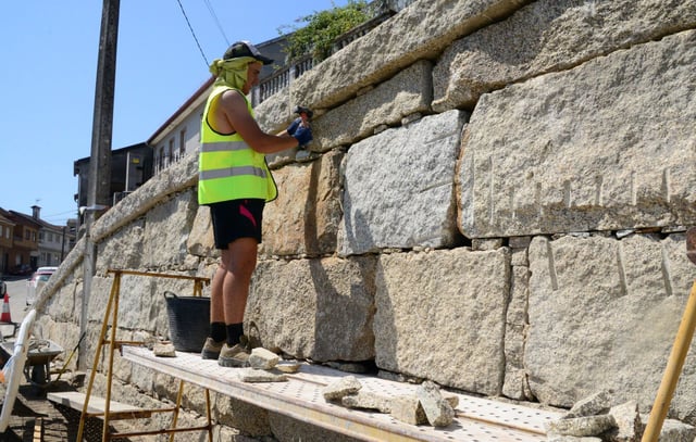 Un obrero, ayer, trabajando en un muro en Bueu y tratando de cubrirse del sol.