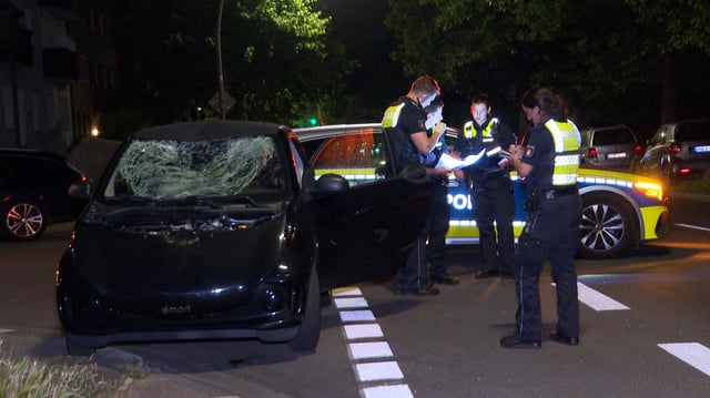 Polizisten stehen neben dem Smart. Die Windschutzscheibe ist deutlich eingedrückt.