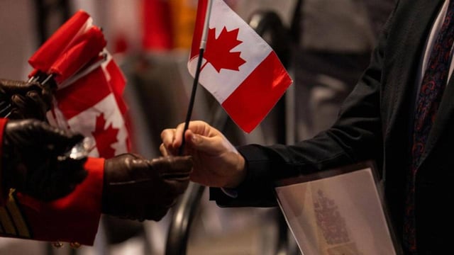 A new Canadian citizen takes a flag during a citizenship ceremony at Canada Place on Canada Day in Vancouver, British Columbia, Canada, on Tuesday. (Bloomberg)
