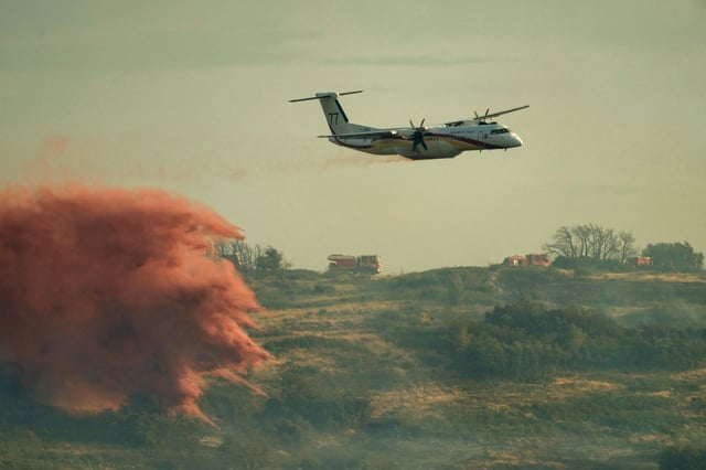 A firefighting plane drops fire retardant on a wildfire in southwest France