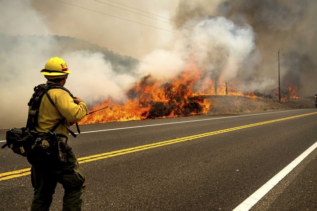 A firefighter battles the Madre Fire along Highway 166 in San Luis Obispo County on Thursday.