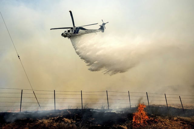A helicopter drops water on the Madre Fire as it burns along Highway 166 in San Luis Obispo County on Thursday. 
