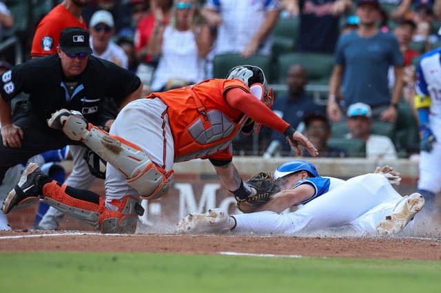 Baltimore Orioles catcher Gary Sánchez, center, tags out Atlanta Braves&#39; Matt Olson, right, at the plate in the fourth inning of a baseball game against the Atlanta Braves, Saturday, July 5, 2025, in Atlanta. (AP Photo/Colin Hubbard)