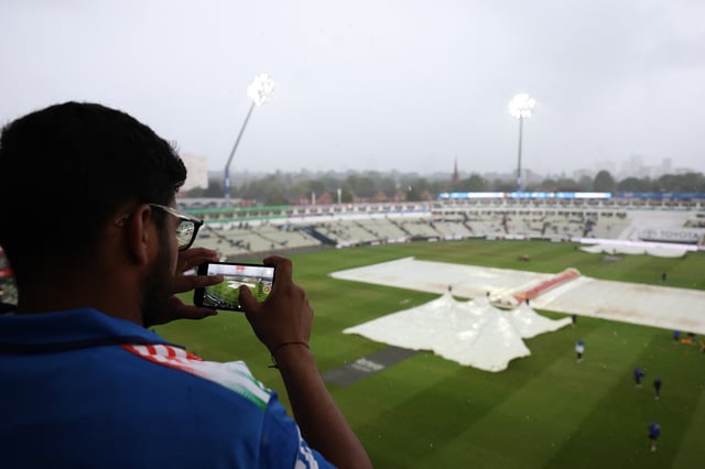 Cricket - Second Test - England v India - Edgbaston Cricket Ground, Birmingham, Britain - July 6, 2025 General view of a spectator recording a video inside the stadium as ground staff members pull covers due to rain Action Images via Reuters/Paul Childs