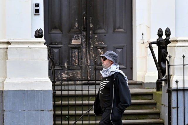 Un homme passe devant la porte principale d'une synagogue de Melbourne partiellement incendiée, le 6 juillet 2025