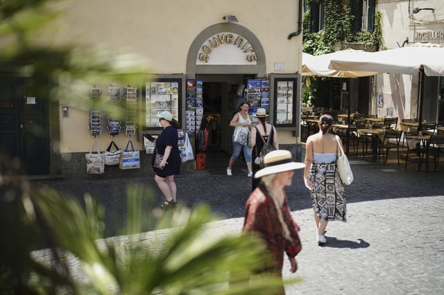 People walk past a souvenir shop in the town of Castel Gandolfo, a historic summer retreat for popes about 30 kilometers southeast of Rome, where Pope Leo XIV will be spending a short period of rest, is seen Wednesday, July 2, 2025. (AP Photo/Andrew Medichini)