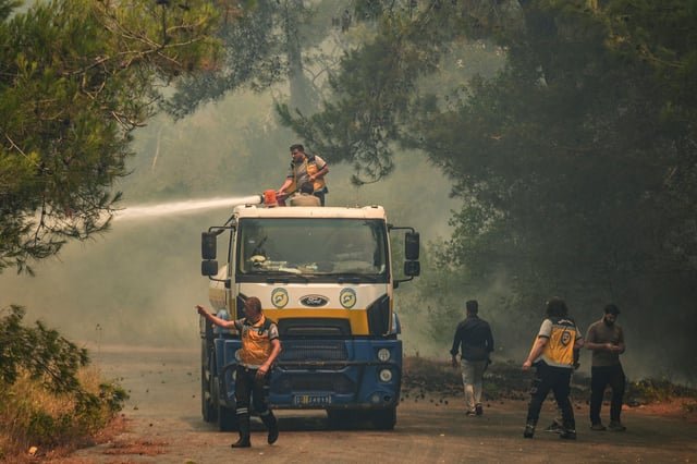 Syrian firefighters battle wildfires sweeping through the forests of Latakia, Syria, on Saturday.